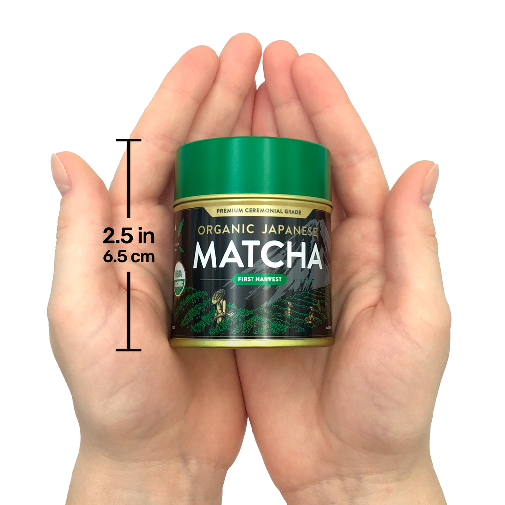 Hands holding a small tin of Organic Japanese Ceremonial Grade Matcha Green Tea Powder with a green lid, labeled "2.5 in, 6.5 cm.