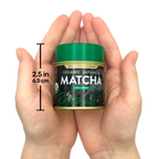 Hands holding a small tin of Organic Japanese Ceremonial Grade Matcha Green Tea Powder with a green lid, labeled "2.5 in, 6.5 cm.