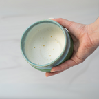 Hand holding an Iguchi Deep Sea Clay Matcha Bowl, featuring a green exterior and speckled white interior evocative of Minoyaki pottery, perfect for serving matcha.