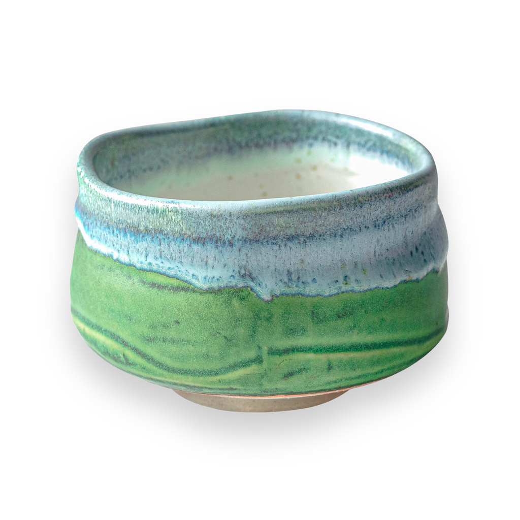 The Iguchi Deep Sea Clay Matcha Bowl showcases a beautiful green and blue glaze against a sleek black backdrop, reminiscent of Minoyaki pottery.