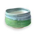 The Iguchi Deep Sea Clay Matcha Bowl showcases a beautiful green and blue glaze against a sleek black backdrop, reminiscent of Minoyaki pottery.