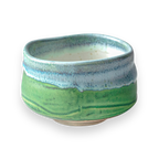 The Iguchi Deep Sea Clay Matcha Bowl showcases a beautiful green and blue glaze against a sleek black backdrop, reminiscent of Minoyaki pottery.