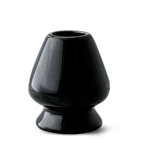 The Black Matcha Whisk Holder from the Black Matcha Whisk Holder and Bamboo Whisk Set exudes a Japanese aesthetic with its glossy ceramic finish, wide base, and narrow top, reminiscent of an elegant matcha whisk holder.