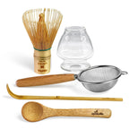 The Clear Glass Matcha Whisk Holder and Bamboo Whisk Set includes a bamboo whisk, clear glass holder, strainer, scoop, and spoon, all elegantly displayed on a white background.