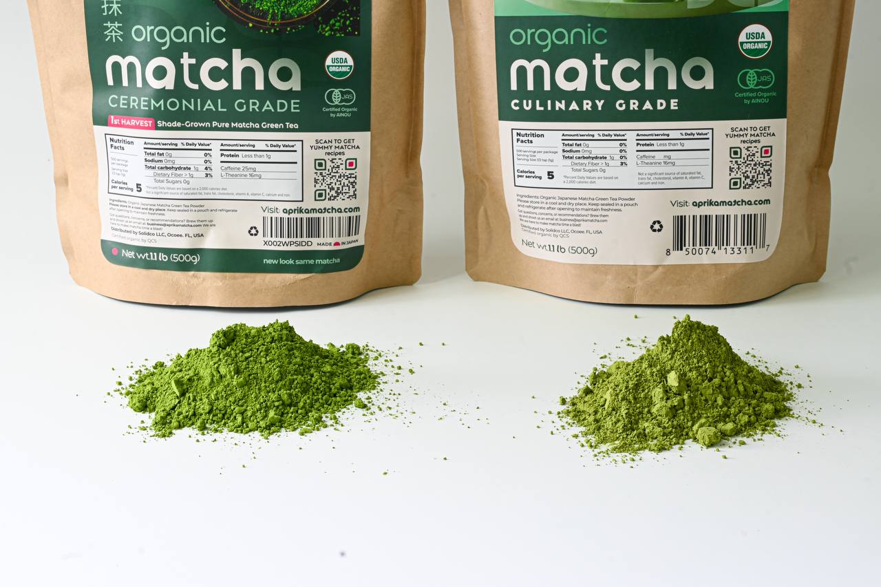 Two piles of culinary grade organic Japanese matcha powder sit before labeled Aprika Life bags of USDA & JAS certified Matcha Powder for Latte, Smoothies, and Recipes—Culinary Grade Green Tea Powder, 3.5 oz.
