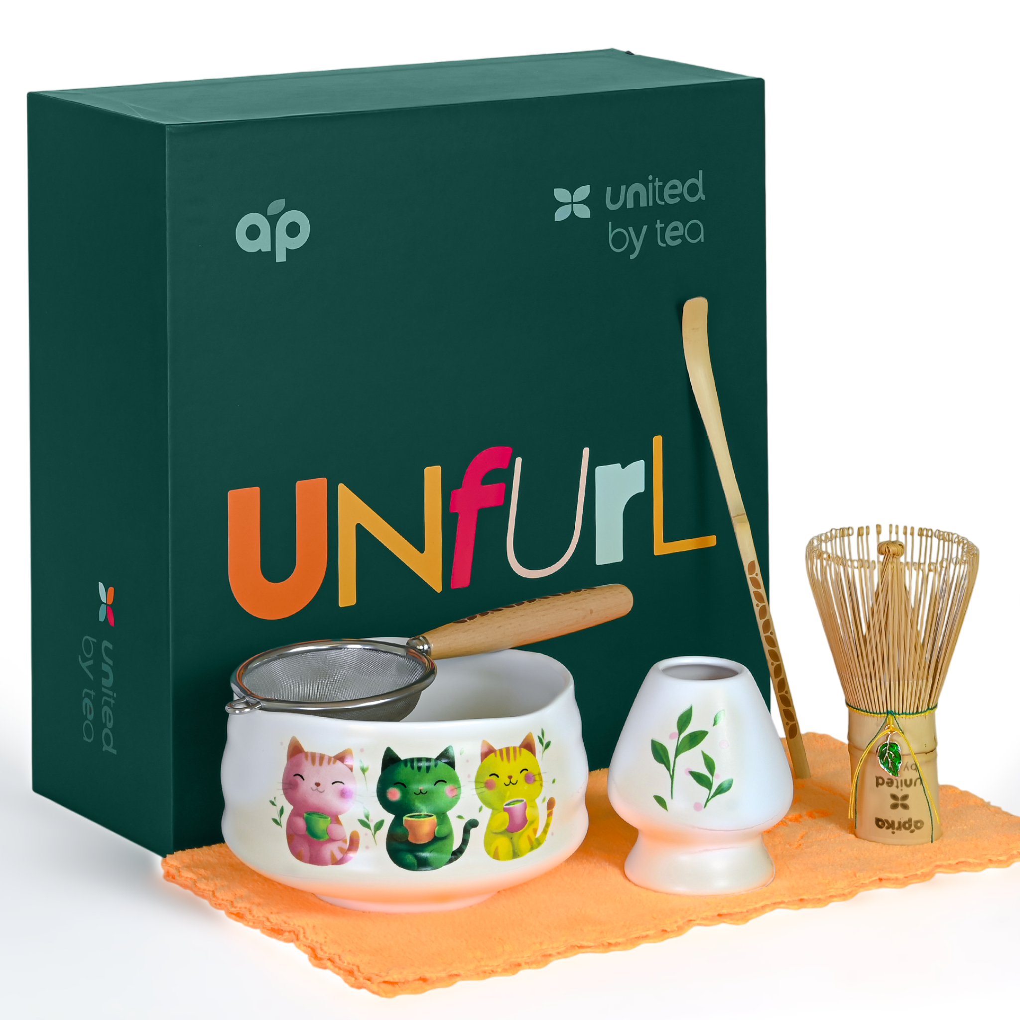 The White Unfurl Matcha Gift Set includes a kawaii cat bowl, cute cat cup, strainer, whisk, scoop, bowl, and orange cloth beside a green gift box—ideal as a white matcha gift set.