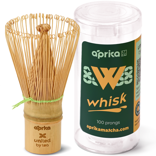 The eco-friendly Bamboo Matcha Whisk (100 Prongs) elegantly rests beside its sleek cylindrical packaging.