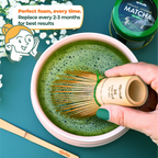 A hand skillfully uses a Dark Matcha Bamboo Whisk (100 Prongs) in a bowl of ceremonial Matcha tea. Replace every 2-3 months for best results—a unique gift idea for tea enthusiasts.